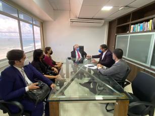 Mesa de vidro com o presidnete do TRT-19, desembargador Marcelo Vieira, no centro e três advogados de um lado e outros dois advogados do outro. Todos prestam atenção à fala de um deles