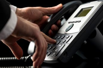 Telefone preto com uma mão de um homem teclando