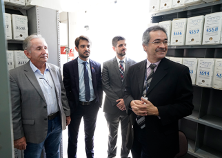 Quatro pessoas de ternos, sendo dois trajando na cor cinza e dois na cor preta
