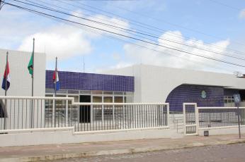 Prédio branco com detalhes azuis, 3 bandeiras à esquerda
