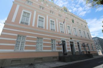 Prédio antigo na cor rosa. Há várias janelas e portas com vidraças