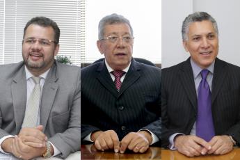 Três homens de paletó e gravata e óculos de grau, sendo um branco e dois morenos, todos de cabelo branco