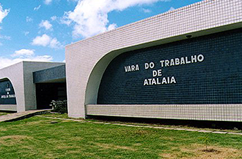 Fachada da VT de Atalaia com o nome Vara do Trabalho de Atalaia sobre uma parede de cor azul escuro; acima, ao lado esquerdo e abaixo da parede azul, paredes de cor cinza claro.