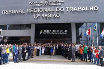 Grupo de pessoas posa de mãos dadas em frente ao TRT-19