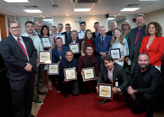 grupo de homens e mulheres com trajes formais segurando uma placa de certificado