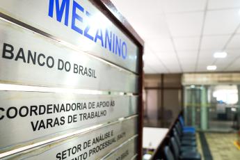 Placa metálica indicativa de locais. Há letras tanto na cor preta,  quanto na tonalidade azul.
