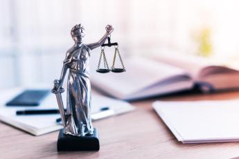 Imagem de uma estátua da deusa da justiça, na cor cinza.