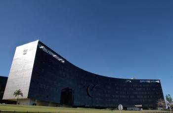 Fachada do TST, uma foto de um  prédio cinza curvo com um céu azul