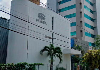 Dois prédios, sendo o da esquerda branco e menor do que o da direita, com o nome TV Gazeta e a logomarca da empresa em letras cinzas escuras; à direita, um edifício maior com janelas de vidros de cor verde.