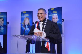 Homem alto, moreno, de cabelo grisalho, toga preta, discursando atrás de um púlpito transparente