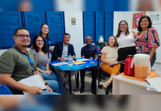 Divresas pessoas reunidas paraa realização de uma foto. A maioria delas está sentada, apenas duas estão de pé.