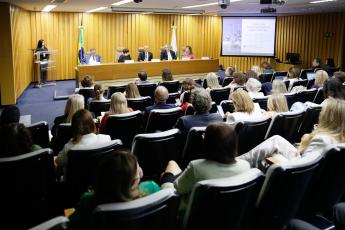 auditório com várias pessoas sentadas e três homens e duas mulheres na mesa de honra
