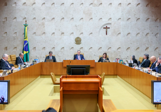 auditório com bancadas de madeira e homens de terno sentados por trás das bancadas