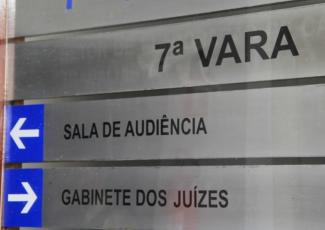 Placa de alumínio na core cinza. Há a indicação da 7ª Vara do trabalho, com seus setores.