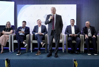 A imagem mostra autoridades e representantes de instituições durante a abertura da Semana do Trabalhador e da Trabalhadora, realizada no auditório da Santa Casa de Misericórdia de Maceió. Em destaque, um homem de terno faz uso da palavra ao microfone, enquanto os demais participantes acompanham a solenidade sentados no palco do evento.