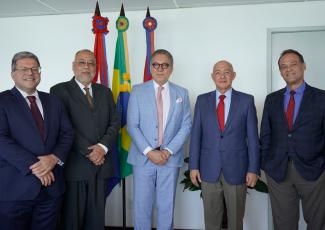 Cinco homens de torno escuro em frente as bandeiras do Brasil e de Alagoas