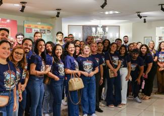 Há um grupo de pessoas dentro de uma sala com muitas luzes e expositores