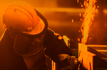 Descrição da imagem: Trabalhador utilizando equipamentos de proteção individual realiza atividade com ferramenta que produz faíscas, destacando a importância da segurança e da prevenção de acidentes no ambiente de trabalho.