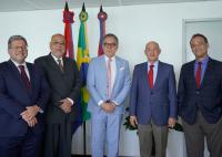 Cinco homens de torno escuro em frente as bandeiras do Brasil e de Alagoas