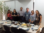 Vária pessoas reunidas em frente a uma mesa com guloseirmas