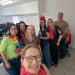 Um grupo de pessoas com colares e  há algumas com arranjos coloridos na cabeça.