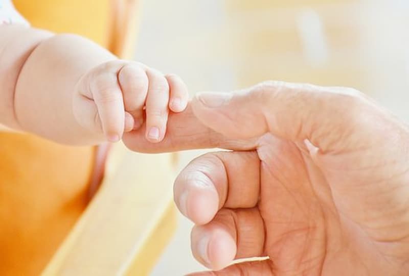 A mão de um bebê segurando a mão do pai 