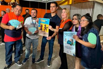 Três homens e três mulheres segurando cartazes e planfletos da campanha "Férias sem trabalho infantil"