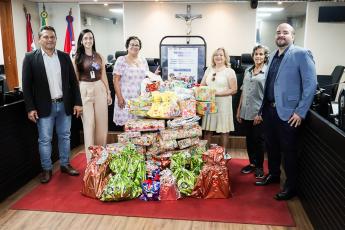 Há quatro mulheres e dois homens posando para foto. Sendo três pessoas se cada lado. Ao centro dessa foto,  há divresas embalagens de presentes.