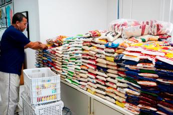 Há um homem de camisa escuro e calça clara. Ele está de frente a uma mesa com váriosvários quilos de alimentos.