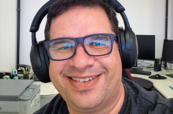 Homem branco de óculos preto usando o handfone preto