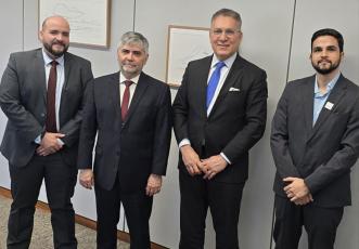 Quatro homens, sendo dois brancos e dois pardos, em pé e de terno escuro