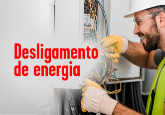 À direita, homem branco de barbar com capacete branco mexendo em um transformador; à esquerda do homem, o nome desligamento de energia escrito em letras vermelhas