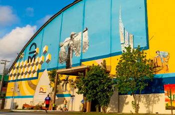 Fachada de um ginásio de esporte colorida nas cores amarelo, azuis claro e escuro