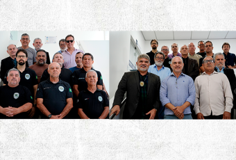 Na foto, várias agentes de segurança em pé, todos posados e de frente para o fotógrafo; a maioria deles está usando blusa preta