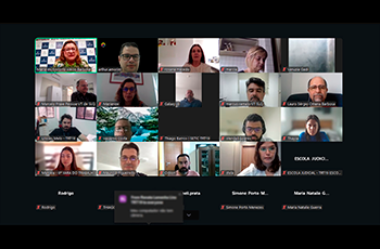 Captura de tela de uma reunião virtual pelo Zoom, com cerca de 20 participantes distribuídos em janelas individuais. Cada participante aparece em seu respectivo ambiente de trabalho ou residência, alguns com câmera ligada e outros com a câmera desligada.