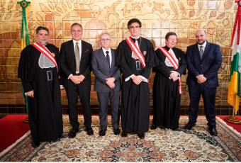 Três homens de toga e três homens de terno em pé em cima de um tapete