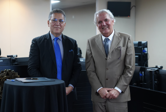 Dois homens pardos, um de terno escuro e outro de terno claro e gravata azul e gravata cinza