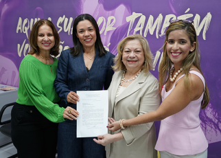 Há quatro mulheres segurando um papel. Elas estão sorridentes e posando para a foto