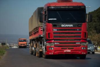 Foto de uma rodovia e, em destaque, uma carreta Scania de cor vermelha