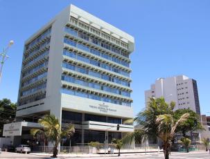 Fachada do TRT de Alagoas com o nome Tribunal Regional do Trabalho da 19ª Região escrito em uma placa de alvenaria de cor preta.