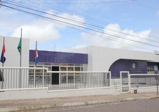 Fachada de Vara do Trabalho de União dos Palmares nas cores azul e branco. Há grades brancas e três bandeireas, sendo duas identificáveis, uma do Brasil e outra do Estado de Alagoas