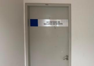 Porta de uma sala identificada com a placa "Secretaria de Recurso de Revista", localizada na sala 402. A porta é cinza, possui maçaneta metálica e está em um corredor de paredes brancas.