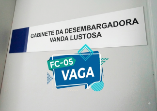 Texto da placa: A placa é retangular, de fundo branco com uma faixa azul vertical na extremidade esquerda. Nela está escrito em letras maiúsculas pretas: "GABINETE DA DESEMBARGADORA VANDA LUSTOSA".  Elemento gráfico sobreposto: Centralizado na parte inferior da imagem, há um gráfico estilo selo/balão de fala azul e verde com o texto "FC-05 VAGA", acompanhado de detalhes geométricos abstratos ao fundo.