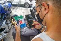 Entregador de aplicativo de costas com celular na mão, aponta a Câmera para  a cartilha "Delivery sim! Superexploração não!", lançada pela Comissão do Trabalho Seguro do TRT/AL 