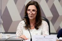 Desa. Jane Granzotto de cabelos soltos, castanhos, usando óculos e camisa de manga longa branca rendada