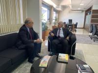 Dois homens de terno escuro, sentados conversando