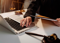 Homem mexendo no computador com um martelo de leilão ao lado