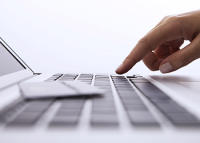 Foto de uma mão com o dedo indicador direito cliclando em um teclado de um notebook cinza