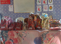 MESA REPLETA DE PRESENTES EM EMBALAGENS ESTAMPADAS NAS CORES VERMELHA, AMARELA 