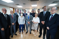 Grupo formado por nove homens vestidos de ternos escuros e ternos cinza e duas mulheres com blusas claras.